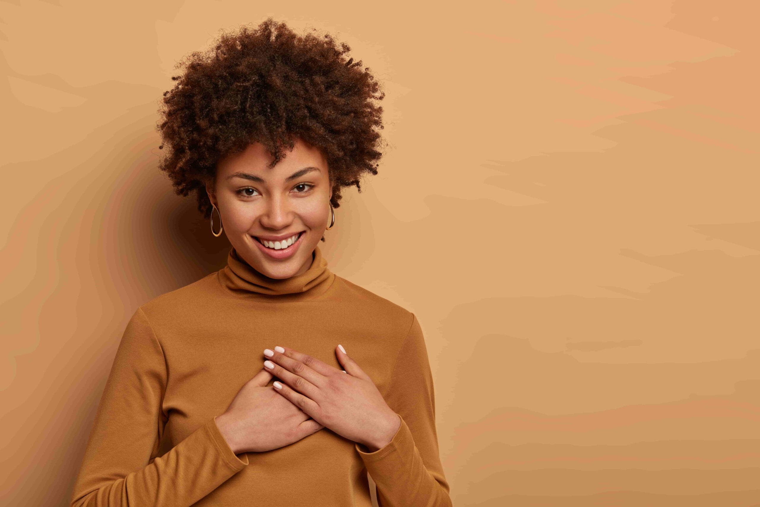 pleased-charming-woman-with-afro-hairstyle-receives-nice-gift-presses-hands-heart-appreciates-help-smiles-gently-feels-very-grateful-min pleased-charming-woman-with-afro-hairstyle-receives-nice-gift-presses-hands-heart-appreciates-help-smiles-gently-feels-very-grateful-min